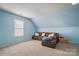 Upstairs room with a large sofa, natural light and carpeting, offering a flexible living space at 1012 Laparc Ln, Indian Trail, NC 28079