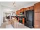 Kitchen boasts wood cabinets, black appliances, tiled floor, and seamless flow into the living and dining areas at 1012 Laparc Ln, Indian Trail, NC 28079