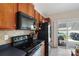 Modern kitchen featuring wood cabinets, black appliances, tile backsplash, and a view of the outdoor patio at 1012 Laparc Ln, Indian Trail, NC 28079