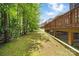 Exterior view of a backyard with a deck and green lawn under mature trees at 10321 Lemington Dr, Mint Hill, NC 28227