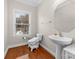 Neat half bathroom with pedestal sink, wood floors, modern toilet and natural light at 10321 Lemington Dr, Mint Hill, NC 28227