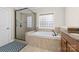 Luxurious bathroom featuring a walk-in shower, a soaking tub, a glass block window, and tiled floors at 10321 Lemington Dr, Mint Hill, NC 28227