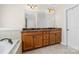 Bathroom featuring wooden cabinets, double sinks, a large mirror, tile flooring, and a soaking tub at 10321 Lemington Dr, Mint Hill, NC 28227