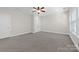 Spacious bedroom with neutral carpet, ceiling fan, and natural light from large windows at 10321 Lemington Dr, Mint Hill, NC 28227