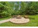 Landscaped firepit area surrounded by mature trees in the backyard at 10321 Lemington Dr, Mint Hill, NC 28227