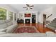 Bright living room featuring a fireplace, hardwood floors, a ceiling fan, and large windows for natural light at 10321 Lemington Dr, Mint Hill, NC 28227