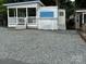 Features a gravel drive next to a park model and a porch with white railings and stairs at 109 Pine St, New London, NC 28127