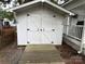The white shed features double doors with a wooden ramp, providing practical storage space at 109 Pine St, New London, NC 28127