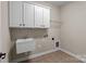 Functional laundry room with white cabinets, utility sink, and tiled floor; perfect for efficient home management at 126 Northbridge Dr, Mooresville, NC 28115