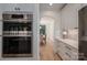 Modern kitchen with stainless steel ovens, white cabinetry, and arched doorway leading to the dining room at 140 Robin Rd, Lincolnton, NC 28092