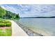 Picturesque waterfront view with a paved path, lush greenery, and stunning lake views, perfect for serene living at 14053 Queens Harbor Rd, Charlotte, NC 28278