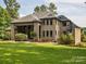 Expansive backyard with lush green lawn and a large brick home featuring a covered patio and manicured landscaping at 172 Barber Loop, Mooresville, NC 28117