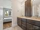 Bathroom boasting a double sink vanity with dark wood cabinets and view to a bedroom with natural light and hardwood floors at 172 Barber Loop, Mooresville, NC 28117