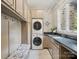 Functional laundry room with a stacked washer and dryer, built-in cabinets, and a utility sink at 172 Barber Loop, Mooresville, NC 28117