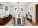 A dining room with a table, neutral chairs, wood floors, modern chandelier and large windows at 2100 Chesterfield Ave, Charlotte, NC 28205