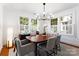A dining room features a wood table and chairs, wood floors, a modern chandelier and large windows at 2100 Chesterfield Ave, Charlotte, NC 28205