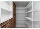 Walk-in pantry with a brick accent wall and white adjustable shelving, perfect for storage and organization at 2100 Chesterfield Ave, Charlotte, NC 28205