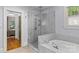 Bathroom featuring glass shower, soaking tub, neutral flooring and paint, plus bright natural light from the window at 2112 Shenandoah Ave, Charlotte, NC 28205
