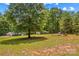 Expansive backyard featuring a mature shade tree, playground, picnic table and red outbuilding on a sunny day at 2229 Old Wilkesboro Rd, Statesville, NC 28625