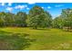 Large backyard, with a swing set, picnic table, and outbuilding, surrounded by lush trees on a sunny day at 2229 Old Wilkesboro Rd, Statesville, NC 28625