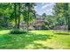 Expansive backyard featuring lush green grass, mature trees, a trampoline, and outdoor deck at 408 Johnsfield Rd, Shelby, NC 28150