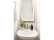 Stylish powder room featuring a sleek pedestal sink, modern faucet, and a decorative mirror at 4226 Acorn St, Charlotte, NC 28205