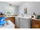 Bright laundry room features a utility sink, modern washer, dryer, wooden cabinetry, and window providing natural light at 4395 Burton Rd, Maiden, NC 28650