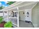 Inviting front porch with hanging plants, a welcome mat, and a charming seating area at 6705 Reddman Rd, Charlotte, NC 28212