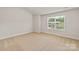 Bright bedroom featuring neutral carpet, vaulted ceilings, and a large window at 7129 Jerimoth Dr, Charlotte, NC 28215