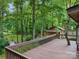 Wooden deck with railing offers a peaceful view of the wooded surroundings and a charming outbuilding at 715 White Oaks Cir, Monroe, NC 28110