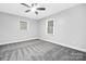 Spacious bedroom with two windows, a ceiling fan and neutral carpet, providing a versatile space at 715 White Oaks Cir, Monroe, NC 28110