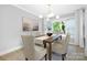 Well-lit dining room with table for six, modern lighting fixture, and a large window overlooking greenery at 715 White Oaks Cir, Monroe, NC 28110