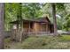 Rustic cabin featuring a covered porch, picket fence, and natural wood siding surrounded by lush greenery at 715 White Oaks Cir, Monroe, NC 28110