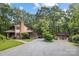 Charming two-story wood home nestled amongst mature trees with a circular gravel driveway and guesthouse at 715 White Oaks Cir, Monroe, NC 28110
