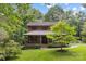 Charming two-story wood home with a covered front porch featuring lovely landscaping and mature trees at 715 White Oaks Cir, Monroe, NC 28110
