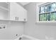 Well-lit laundry room with upper cabinets, hook-ups and a view to the outdoors at 715 White Oaks Cir, Monroe, NC 28110