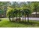 Tranquil yard featuring a charming wooden swing hanging from a lush, green-covered pergola at 715 White Oaks Cir, Monroe, NC 28110
