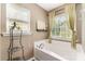 Inviting bathroom with garden tub and a window letting in natural light and view of the outside at 10237 Broken Stone Ct, Charlotte, NC 28214