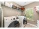 Bright laundry room with white washer, dryer, tile floor, storage shelf and window at 10237 Broken Stone Ct, Charlotte, NC 28214