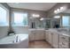 Bright bathroom featuring a corner tub, double vanity with white cabinets, and ample natural light at 104 Wingstem Ct, Mooresville, NC 28117