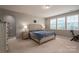 Well-lit bedroom features a queen bed, side tables with lamps, a view of the neighborhood, and a stationary bike at 104 Wingstem Ct, Mooresville, NC 28117