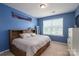 Vibrant bedroom with blue walls featuring a platform bed and large window, providing natural light and a cozy feel at 104 Wingstem Ct, Mooresville, NC 28117