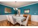 Elegant dining room with blue walls, hardwood floors, chandelier, and a table set for six at 104 Wingstem Ct, Mooresville, NC 28117
