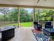Enjoy the view from this covered patio with seating area overlooking a sprawling green lawn and natural landscape at 106 Pier Point Dr, Stony Point, NC 28678