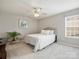 Bright bedroom features neutral walls, ceiling fan, and carpet, complete with a cozy bed and decorative plant at 11332 Anna Rose Rd, Charlotte, NC 28273