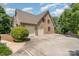 Side view of a brick house with a three-car garage, beautiful landscaping, and a spacious driveway at 135 Oak Creek Dr, Rockwell, NC 28138