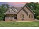 Charming brick home featuring a cozy front porch, well-manicured lawn, and tasteful landscaping at 135 Oak Creek Dr, Rockwell, NC 28138