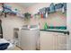 Functional laundry room with washer, dryer, utility sink, storage shelves and patterned wall paper at 135 Oak Creek Dr, Rockwell, NC 28138