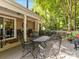 Outdoor deck area featuring multiple metal chairs and tables surrounded by a treed yard at 13600 Seastone Ln, Pineville, NC 28134
