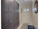Entryway featuring built-in gray storage cabinets, white door, neutral walls, and patterned rug at 18205 Royal Oak Rd, Charlotte, NC 28278